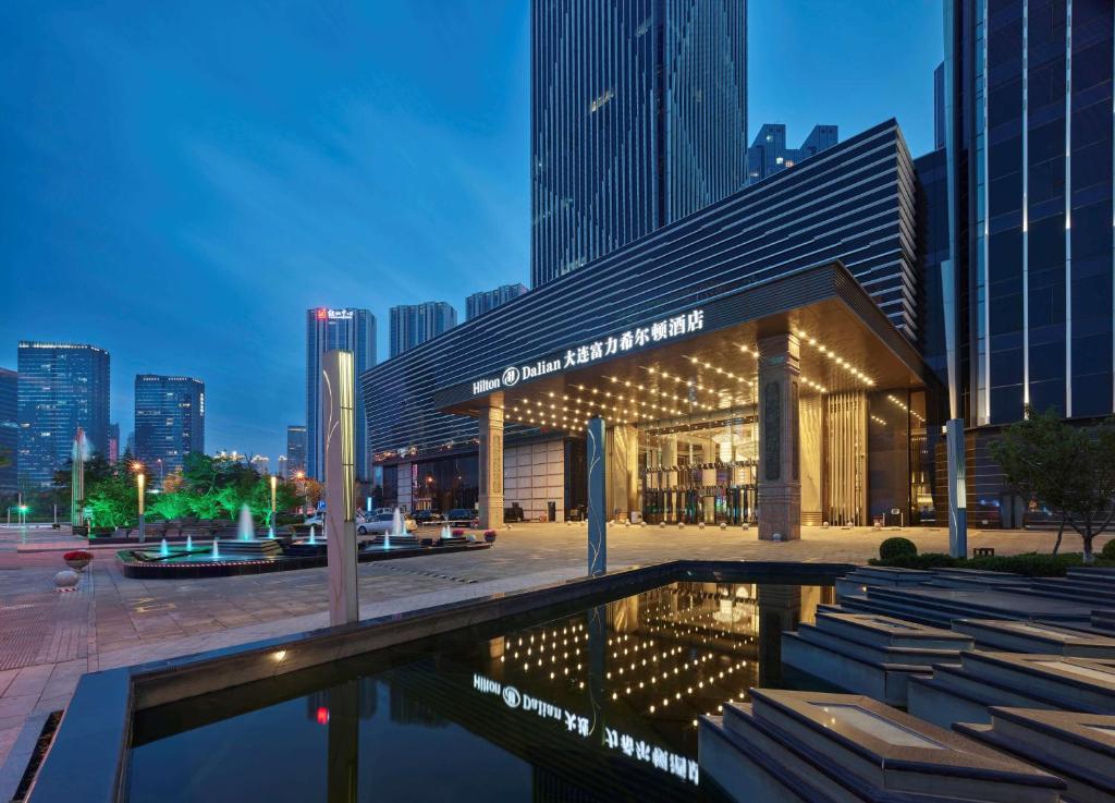 a building with a pool in front of a city at Hilton Dalian in Dalian