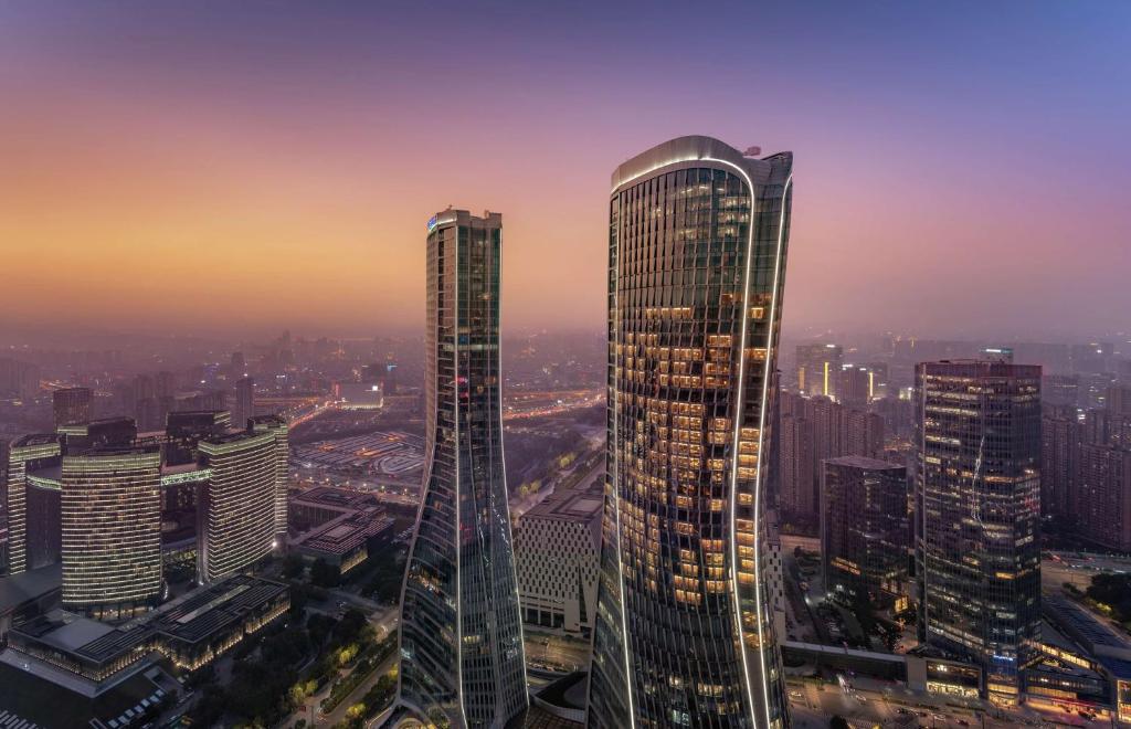 dos rascacielos altos en una ciudad al atardecer en Conrad Hangzhou, en Hangzhou