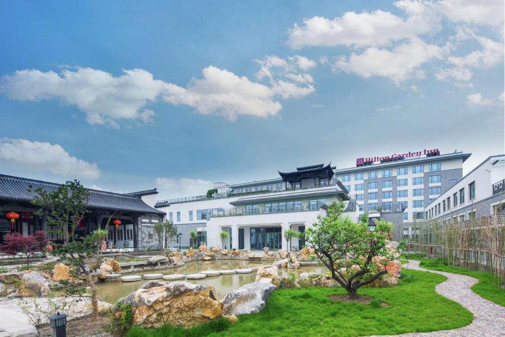 ein Hotel mit einem Teich vor einem Gebäude in der Unterkunft Hilton Garden Inn Qidong in Qidong