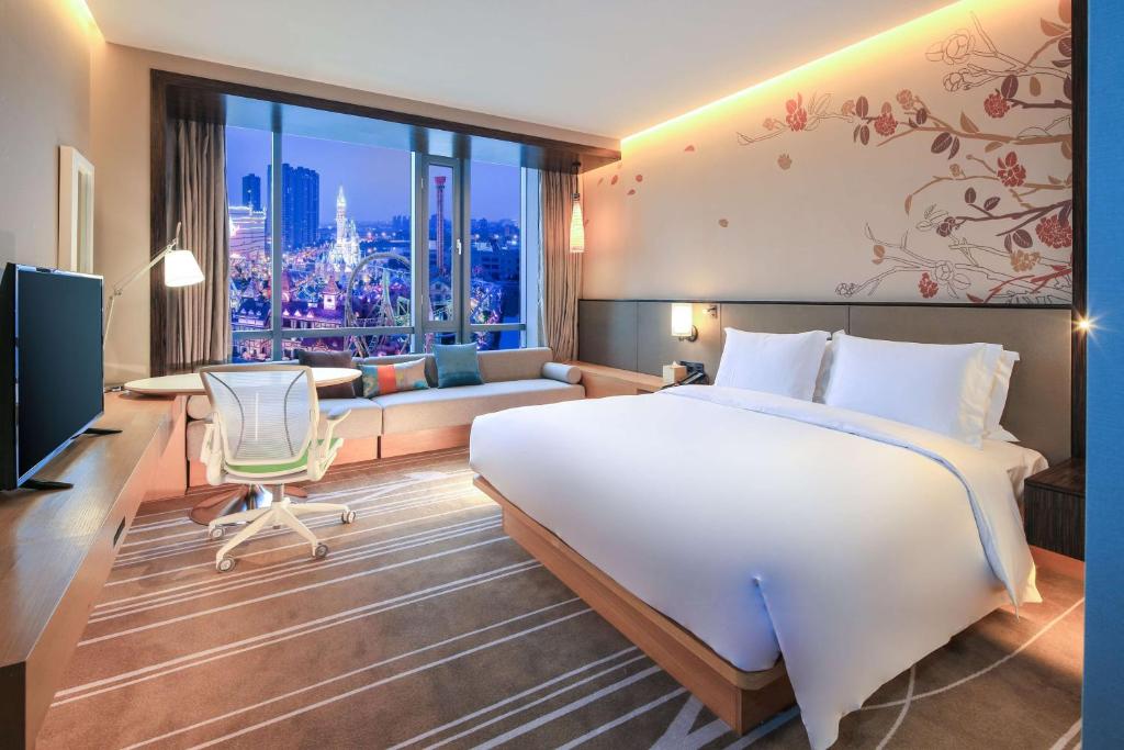 a hotel room with a large bed and a couch at Hilton Garden Inn Ningbo in Ningbo