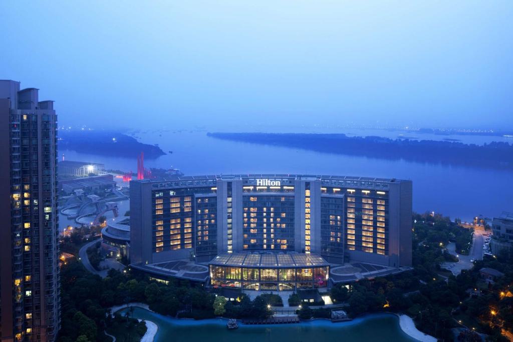eine Luftansicht eines Gebäudes in der Nacht mit einem Fluss in der Unterkunft Hilton Nanjing Riverside in Nanjing