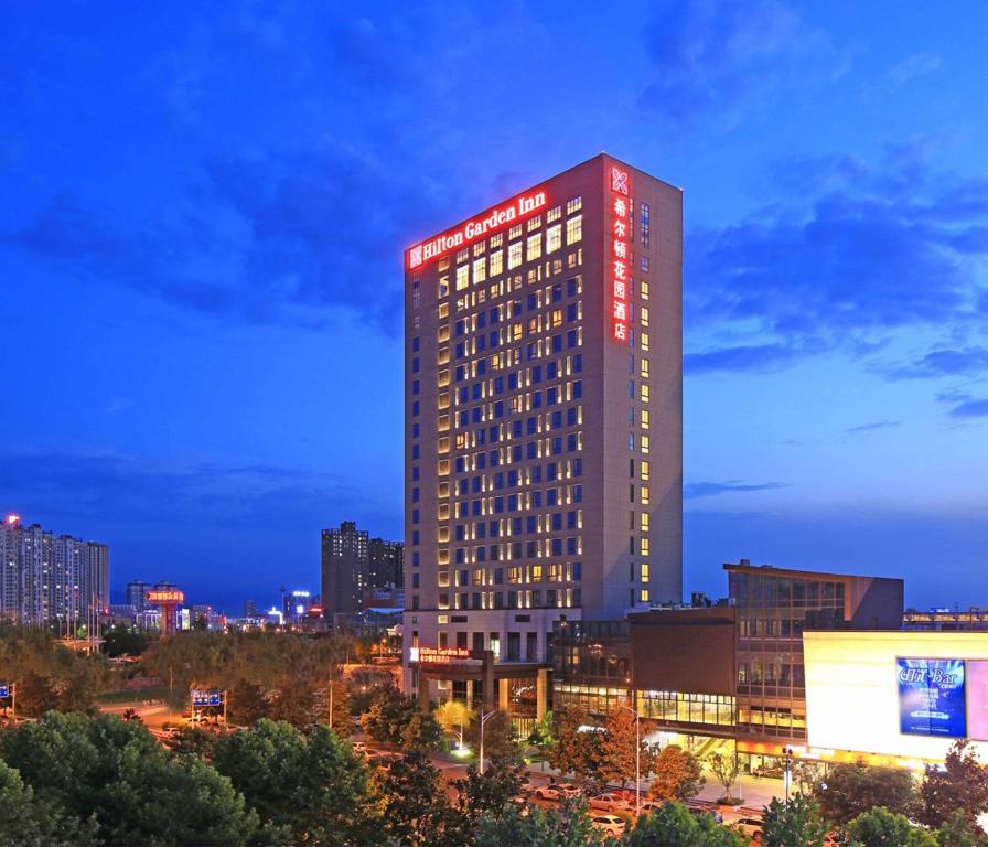 a tall red building with lights on it at night at Hilton Garden Inn Xi'an High-Tech Zone in Xi'an