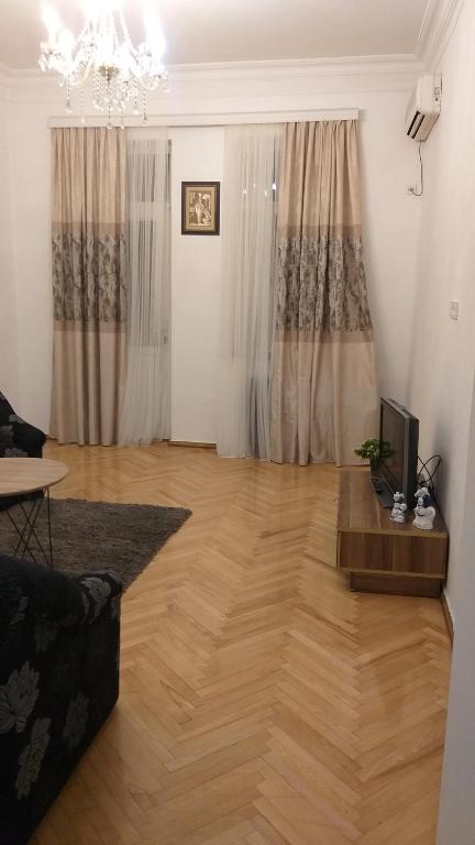 ein Wohnzimmer mit Holzboden und einem TV in der Unterkunft poti apartment in Poti