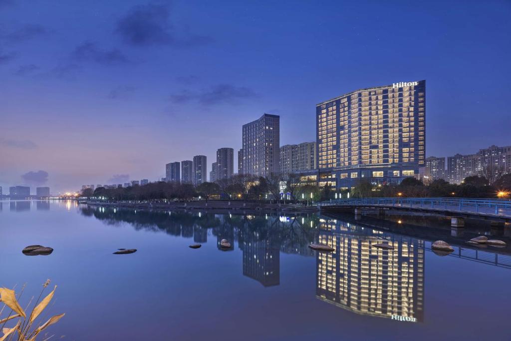 Blick auf eine Stadt mit Fluss und Gebäuden in der Unterkunft Hilton Suzhou Yinshan Lake in Suzhou