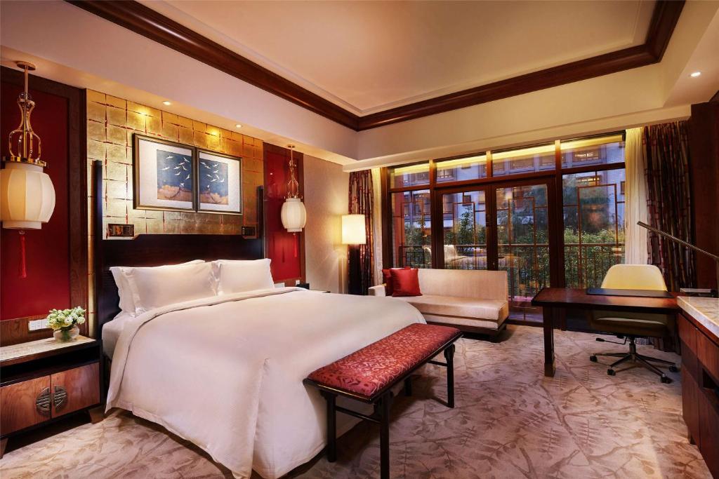 een slaapkamer met een groot wit bed en een bureau bij Hilton Tianjin Eco-City in Binhai