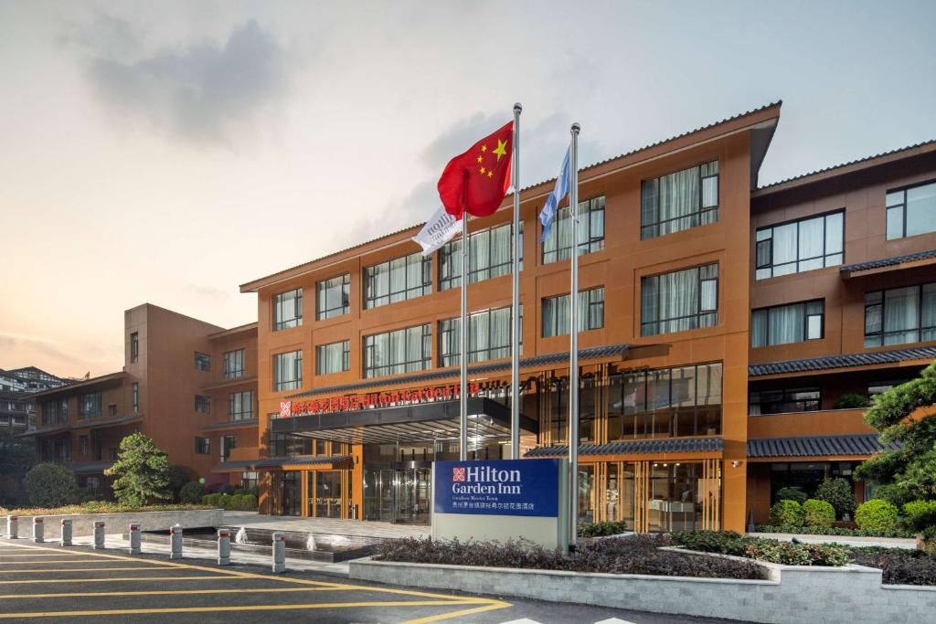 un bâtiment avec deux drapeaux devant lui dans l'établissement Hilton Garden Inn Guizhou Maotai Town, à Maotai