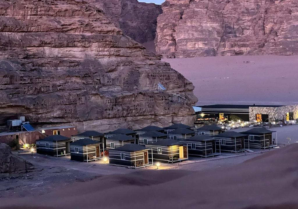 grupa domków letniskowych przed klifem w obiekcie Rum Planet Camp w mieście Wadi Rum