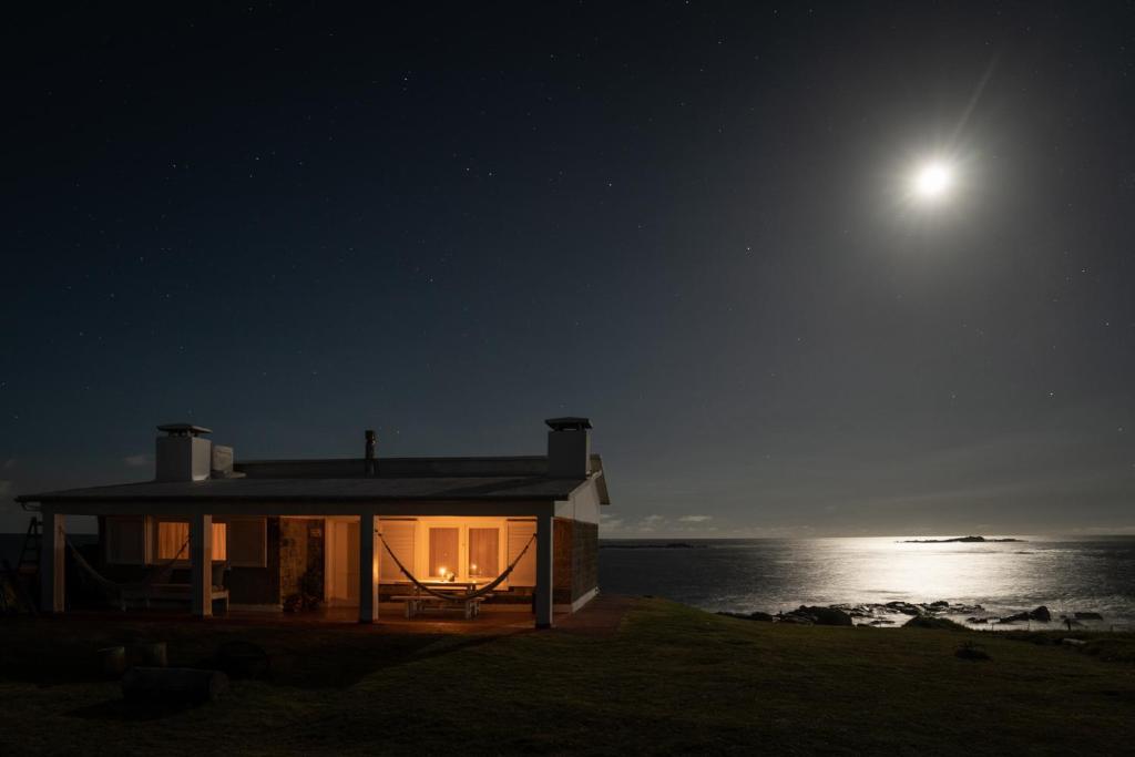 una casa sulla spiaggia di notte con la luna di Palacio de la luna, casa única frente al mar a Cabo Polonio