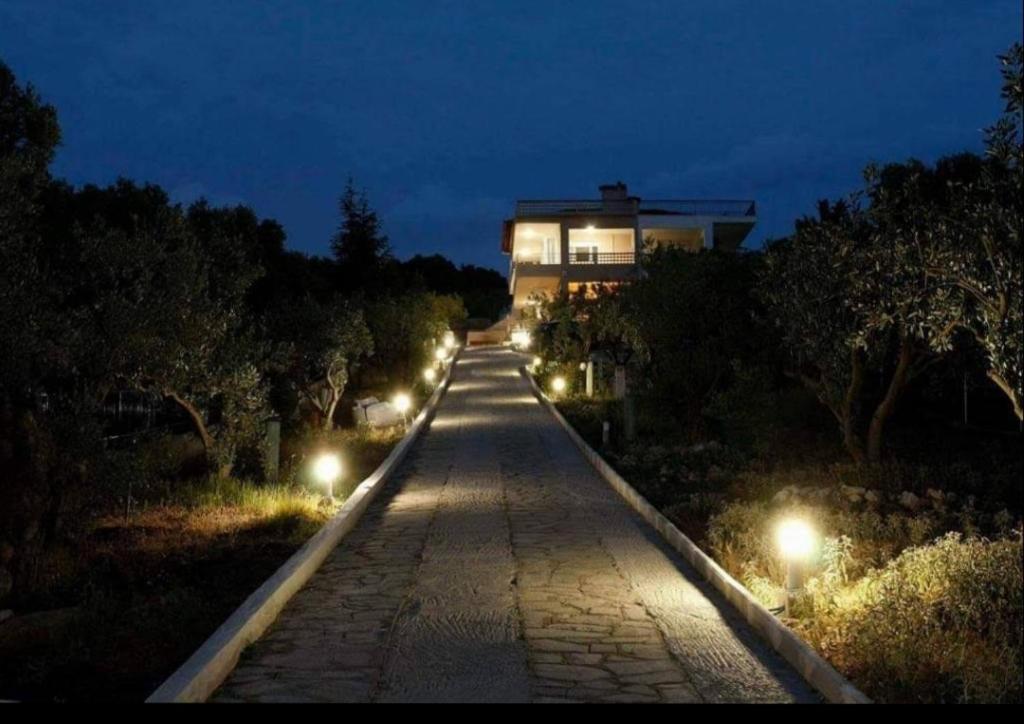a walkway with lights in front of a building at night at OLIVE & SEA in Nea Moudania