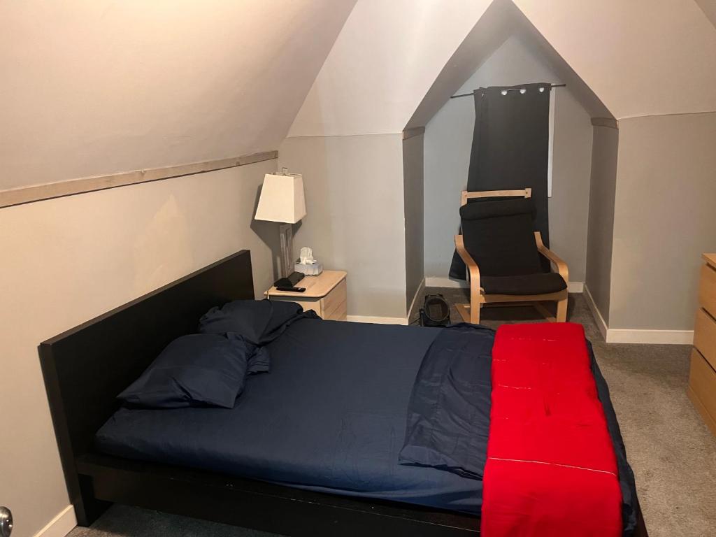 um quarto com uma cama com um cobertor vermelho e uma cadeira em Guest House em Winnipeg
