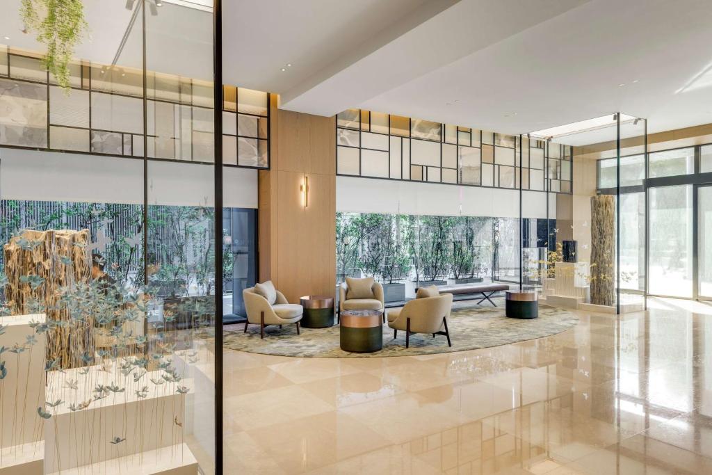 a lobby with chairs and tables and glass walls at DoubleTree by Hilton Taipei Zhongshan in Taipei