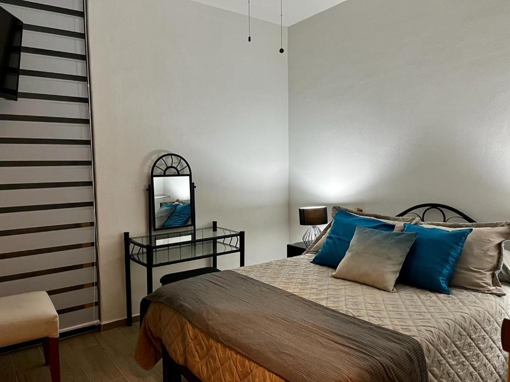 um quarto com uma cama com almofadas azuis e um espelho em Departamento Lago de Chapala con Roof Top. em Jocotepec