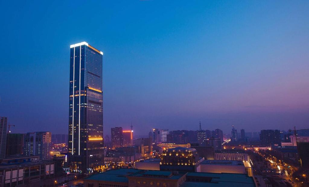 a city skyline with a tall building at night at Hilton Shijiazhuang in Shijiazhuang