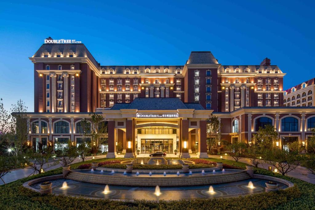 a hotel with a fountain in front of a building at Doubletree By Hilton Qingdao Oriental Movie Metropolis in Huangdao