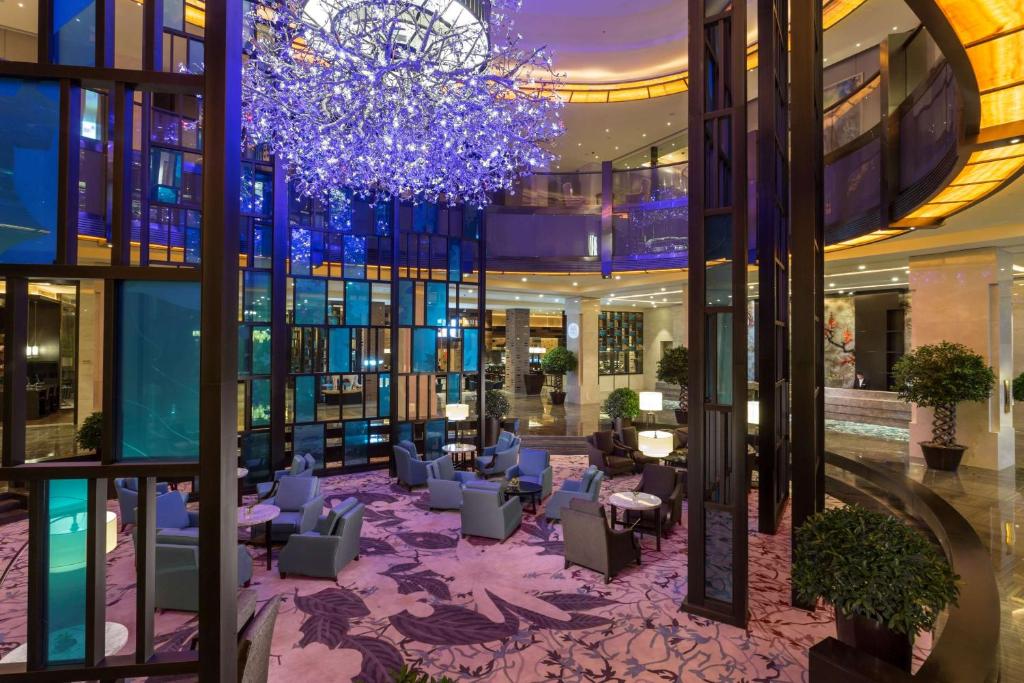 a lobby with chairs and a chandelier in a building at Hilton Changzhou in Changzhou