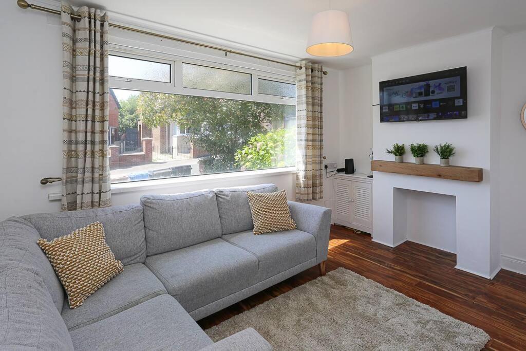 a living room with a gray couch and a fireplace at 2 bedroom house in Belfast with garden in Belfast