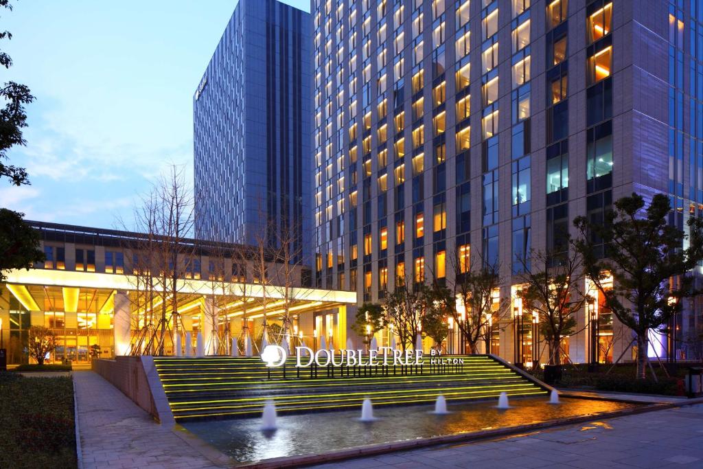 un bâtiment avec une fontaine en face d'un bâtiment dans l'établissement DoubleTree by Hilton Hangzhou East, à Hangzhou