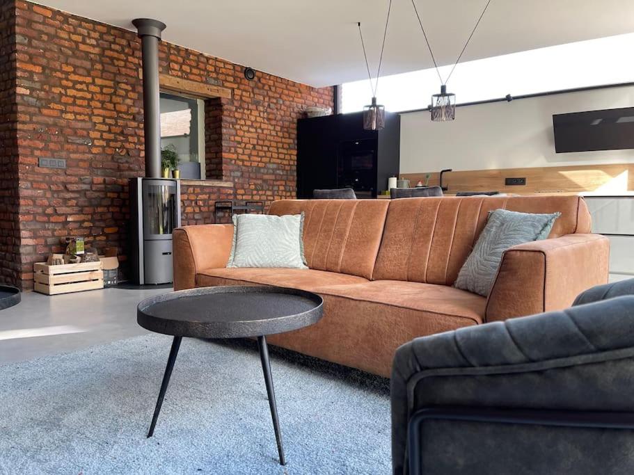sala de estar con sofá marrón y mesa en Gîte 'Au bout du Tige' en Braives