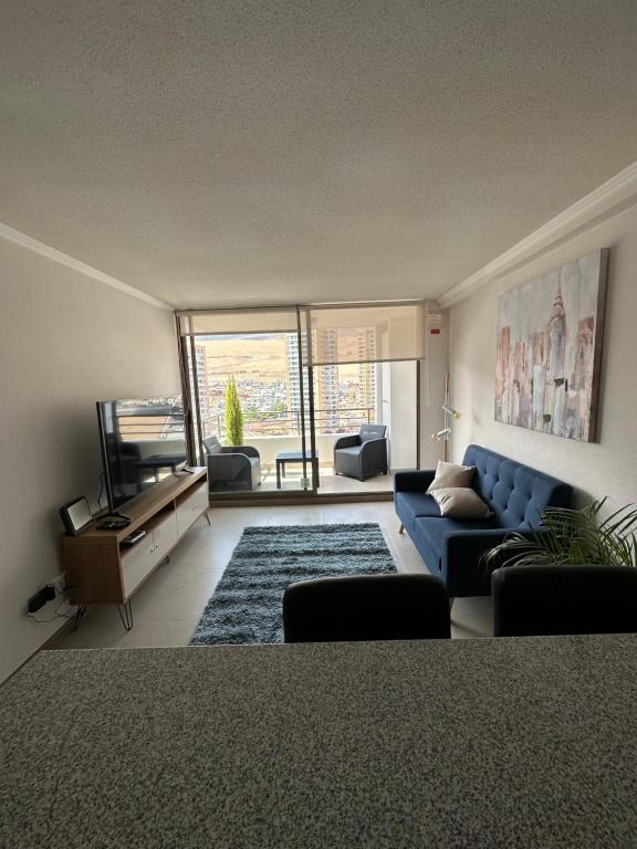 ein Wohnzimmer mit einem blauen Sofa und einem Fernseher in der Unterkunft Departamento 1D1B Condominio Altos de Huayquique in Iquique