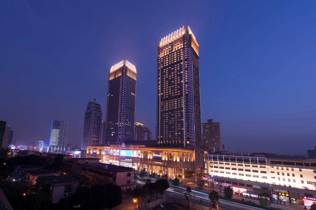 a city skyline with tall skyscrapers at night at Hilton Zhongshan Downtown in Zhongshan