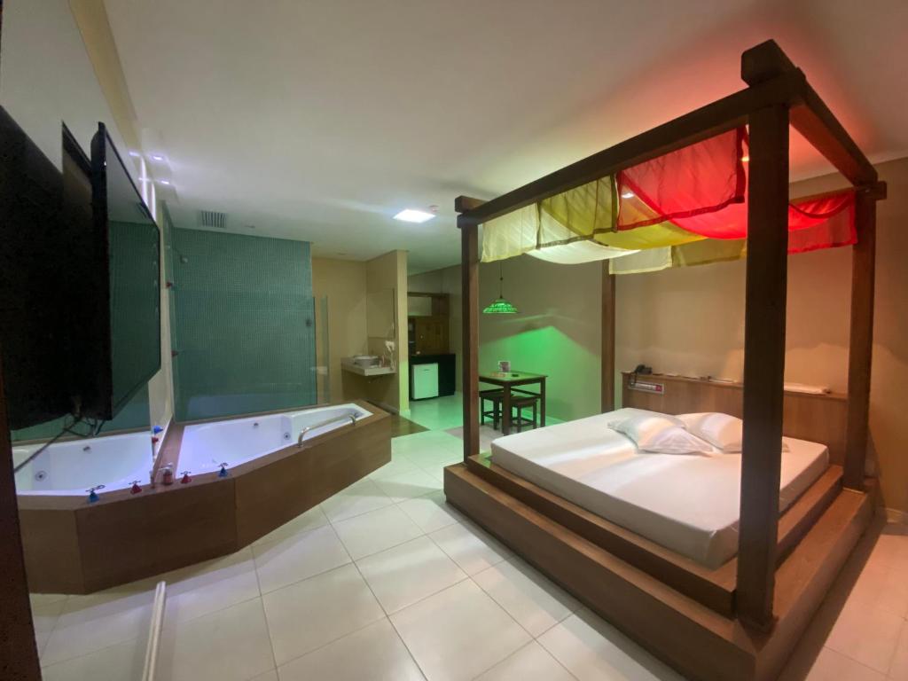 a bedroom with a bed and a bath tub at Passione Criciúma - Adult Only in Criciúma