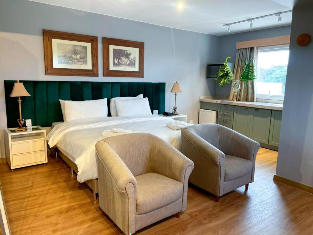 - une chambre avec un grand lit et deux chaises dans l'établissement ibis Catanduva, à Catanduva