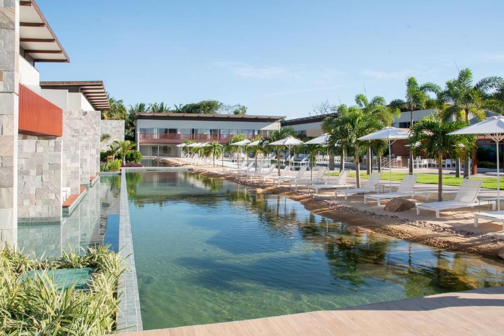 a pool at the resort with chairs and umbrellas at île de Pipa - Ma Plage Hotel in Pipa