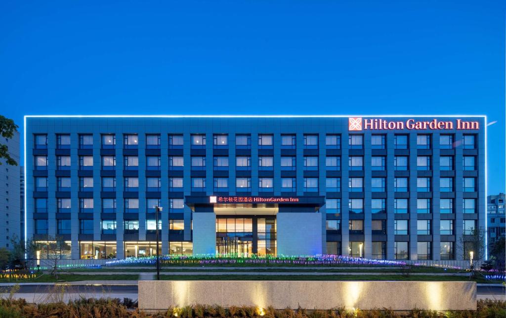 um hotel com um edifício iluminado à noite em Hilton Garden Inn Changchun Economic Development Zone em Changchun