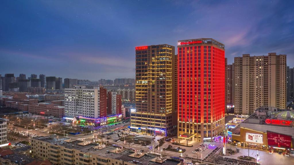 Ein hohes rotes Gebäude in einer Stadt in der Nacht in der Unterkunft Hilton Garden Inn Heze in Heze