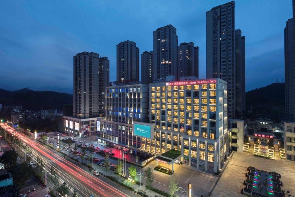 un perfil urbano con edificios altos por la noche en Hilton Garden Inn Shiyan, en Shiyan