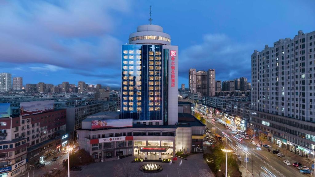 a lit up building in a city at night at Hilton Garden Inn Anshan Haicheng in Anshan