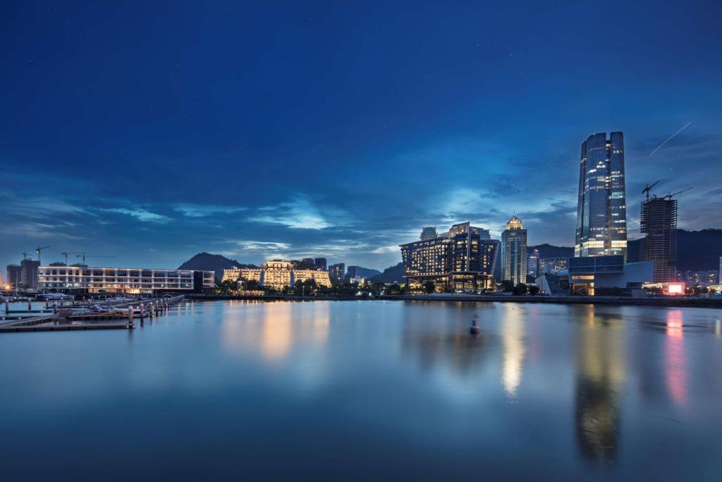 un perfil urbano por la noche con una gran masa de agua en Hilton Shenzhen Shekou Nanhai, en Shenzhen