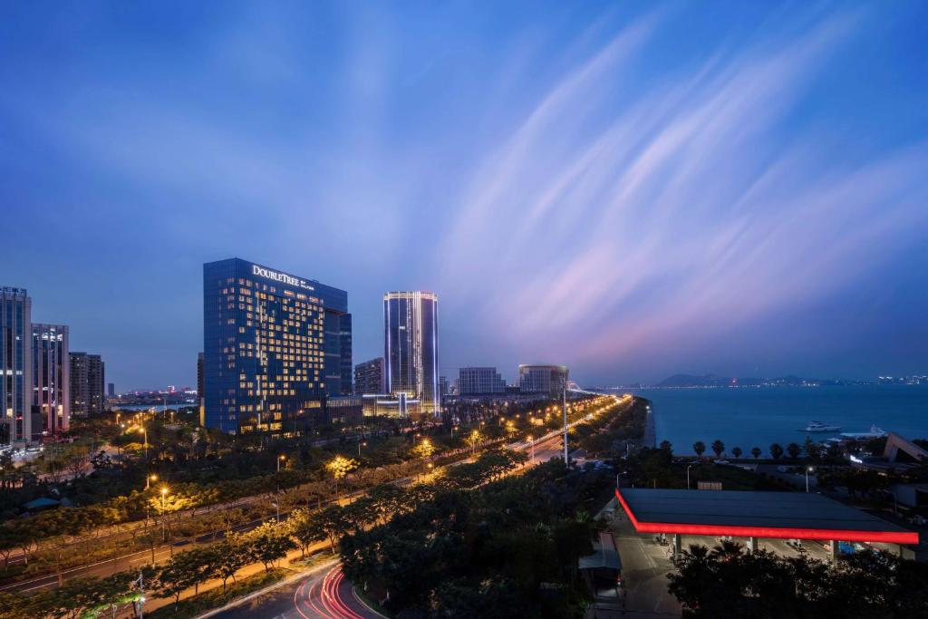 DoubleTree by Hilton Hotel Xiamen - Wuyuan Bay في شيامن: اطلاله على مدينه في الليل مع اناره