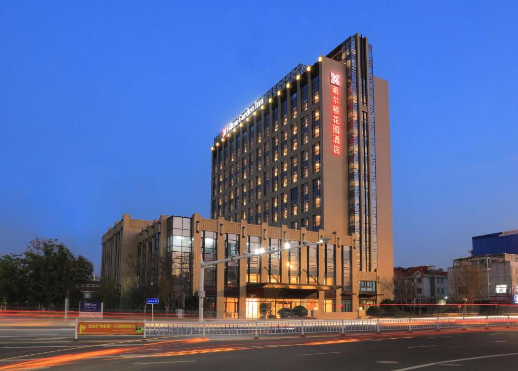 wysoki budynek z znakiem na boku w obiekcie Hilton Garden Inn Changzhou Jintan w mieście Changzhou