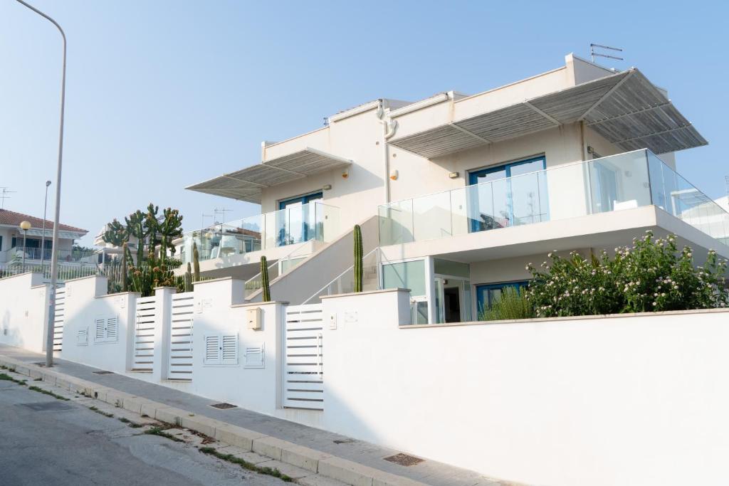 a white house with a white fence at Edilia Vacanze in Marina di Ragusa