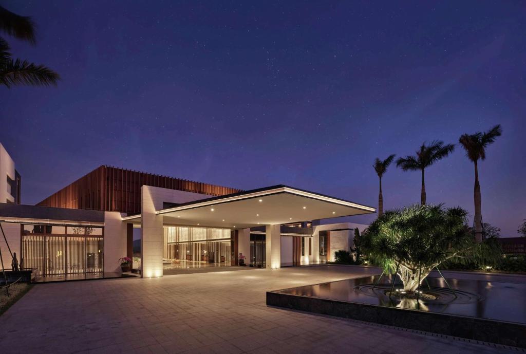 een groot gebouw met palmbomen ervoor bij Doubletree Resort By Hilton Hainan - Xinglong Lakeside in Wanning