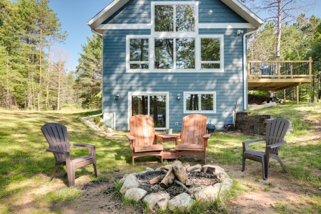 a group of chairs around a fire pit in front of a house at Cozy Northwoods Cabin with Private Lake Access in Eagle River