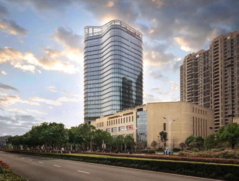 a tall glass building next to a road at DoubleTree By Hilton Ningbo Beilun in Ningbo