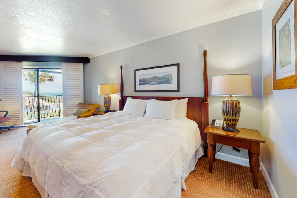 Un dormitorio con una gran cama blanca y una mesa con lámparas. en Condos in Kauai Beach Resort, en Hanamaulu