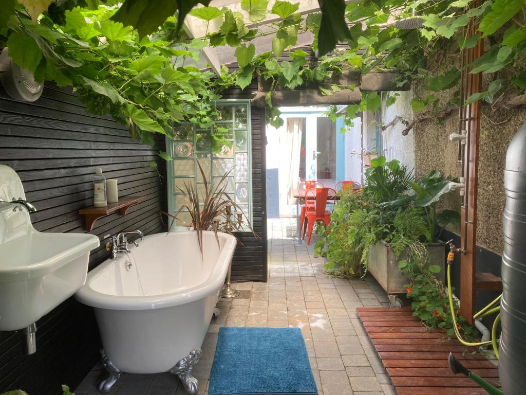 uma casa de banho com uma banheira, um lavatório e plantas em The Vineyard (Home of the think pod) em Portsmouth