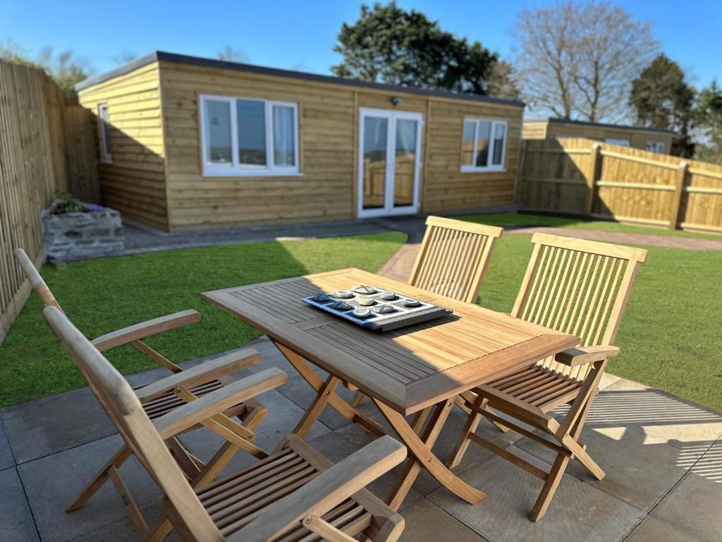 a wooden table and chairs on a patio with a house at Citrus Chalet in Redruth