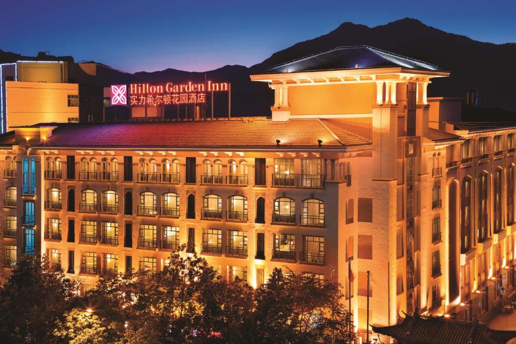 麗江市にあるHilton Garden Inn Lijiangの夜に屋根の上に看板が立っている建物