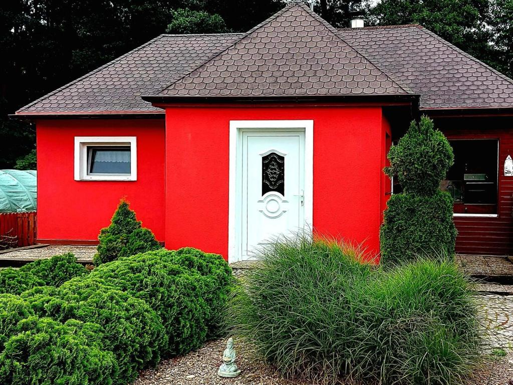 a red house with a white door in a yard at holiday home, Nowe Warpno in Nowe Warpno