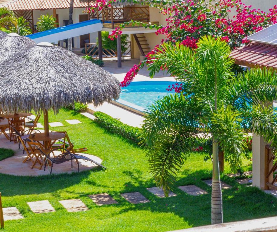 a resort with a pool and a straw umbrella and a palm tree at POUSADA OBAH VILLAGE in Prea