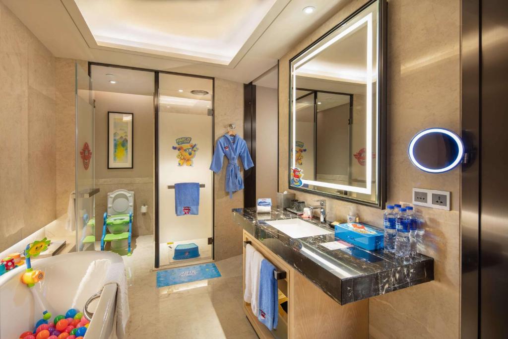 La salle de bains est pourvue d'un lavabo, d'une baignoire et d'un miroir. dans l'établissement DoubleTree by Hilton Hotel Anshun, à Anshun