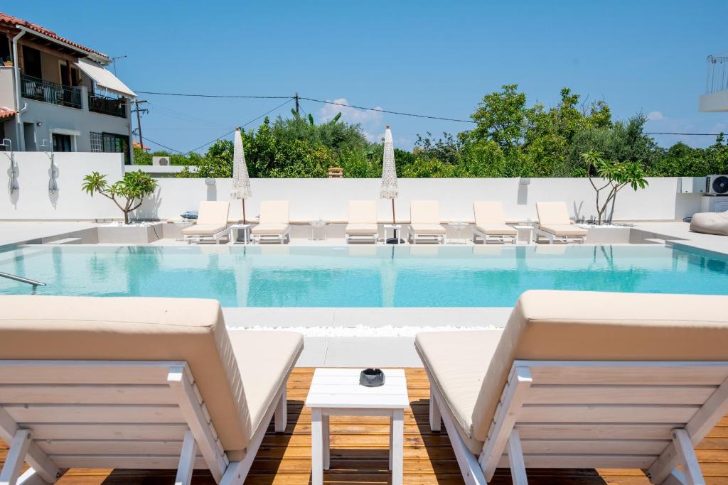 una piscina con sedie bianche e un tavolo di Ennea Suites-Flame suite a Flámbouras