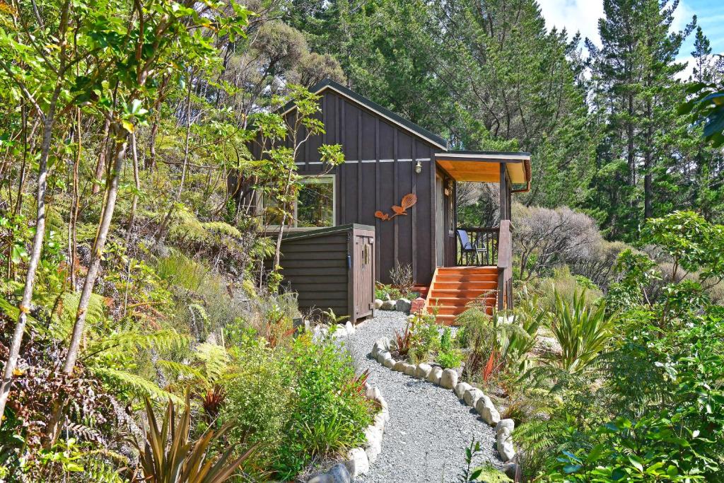 a garden with a small house in the woods at Remutaka retreat in Upper Hutt