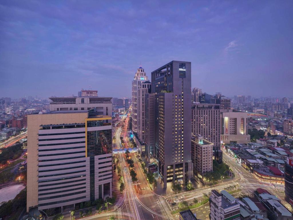 uma cidade com muitos edifícios altos e uma rua com carros em Hilton Taipei Sinban em Taipei
