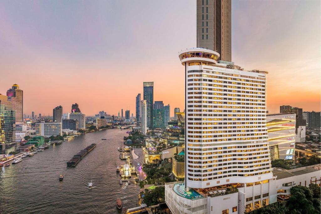 ein hohes Gebäude neben einem Fluss in einer Stadt in der Unterkunft Millennium Hilton Bangkok in Bangkok