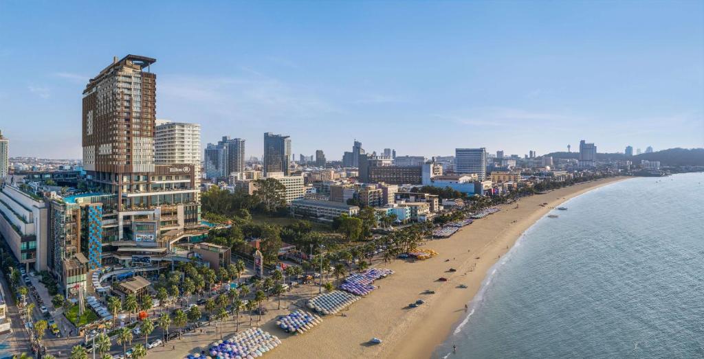 a beach with umbrellas and buildings and the ocean at Hilton Pattaya in Pattaya